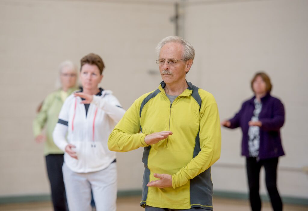 Four older adults practice tai-chi during a class