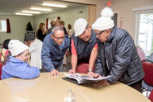 Older adults celebrating Older Americans Month by sharing stories while looking at photographs