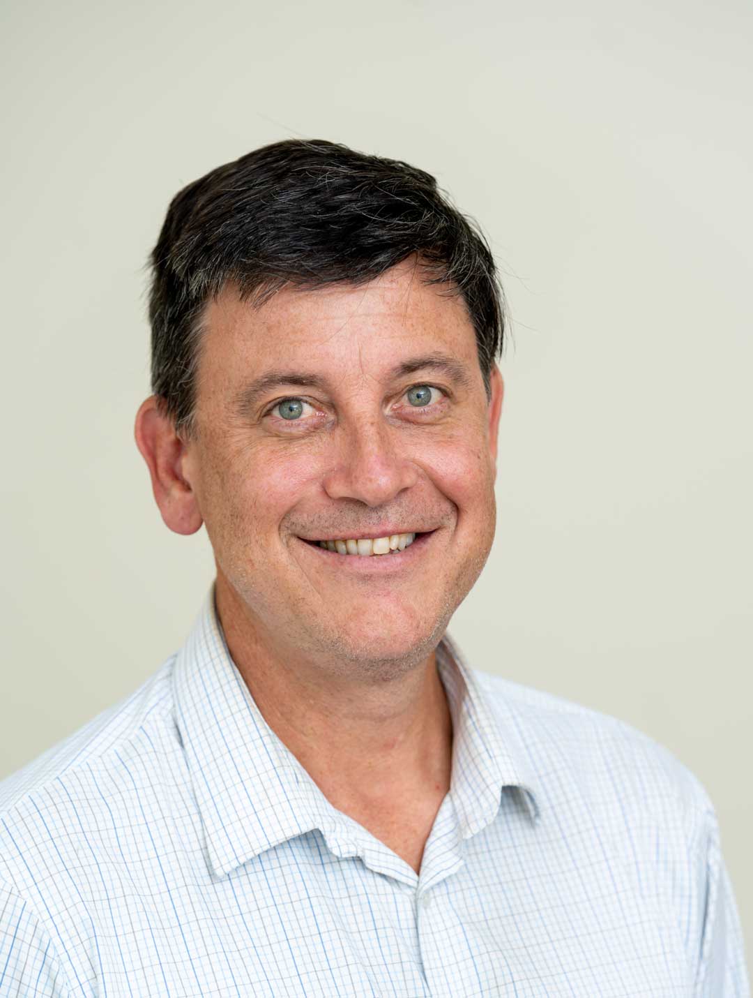 Man with dark hair and light blue shirt smiling