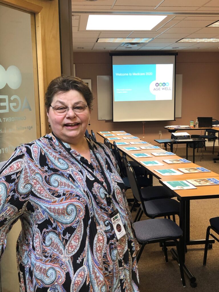 Photograph of Age Well State Health Insurance Program staff member, Sharon, smiling directly to camera. Sharon is about to teach a Medicare Open Enrollment Period class.